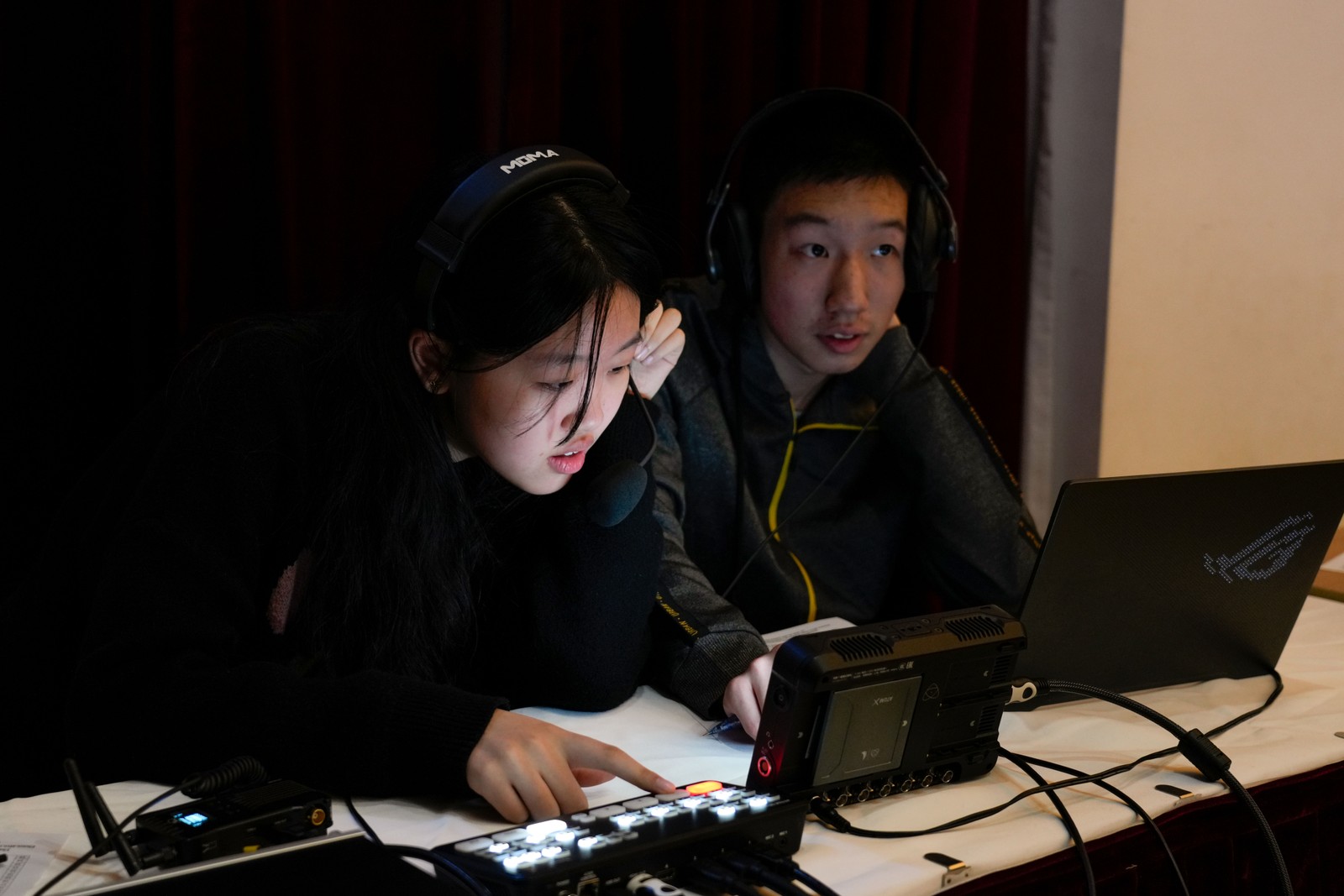 Two people working at a broadcast control desk