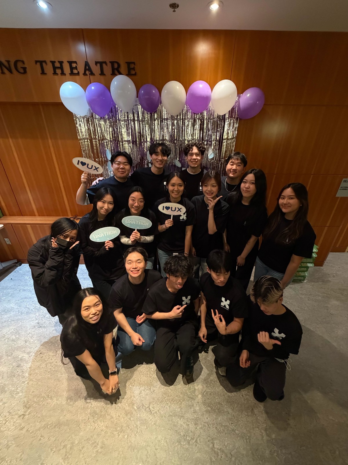 The UX Hub group posing with balloons in a theatre lobby